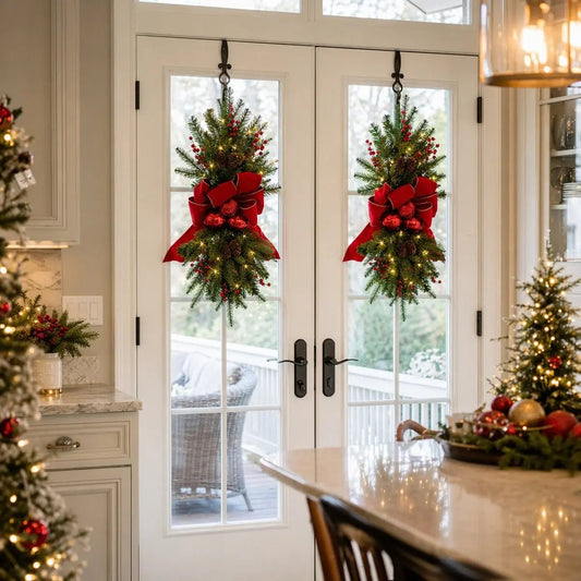 Artificial Christmas swag wreath with red bow and pine cones hanging on a front door entryway