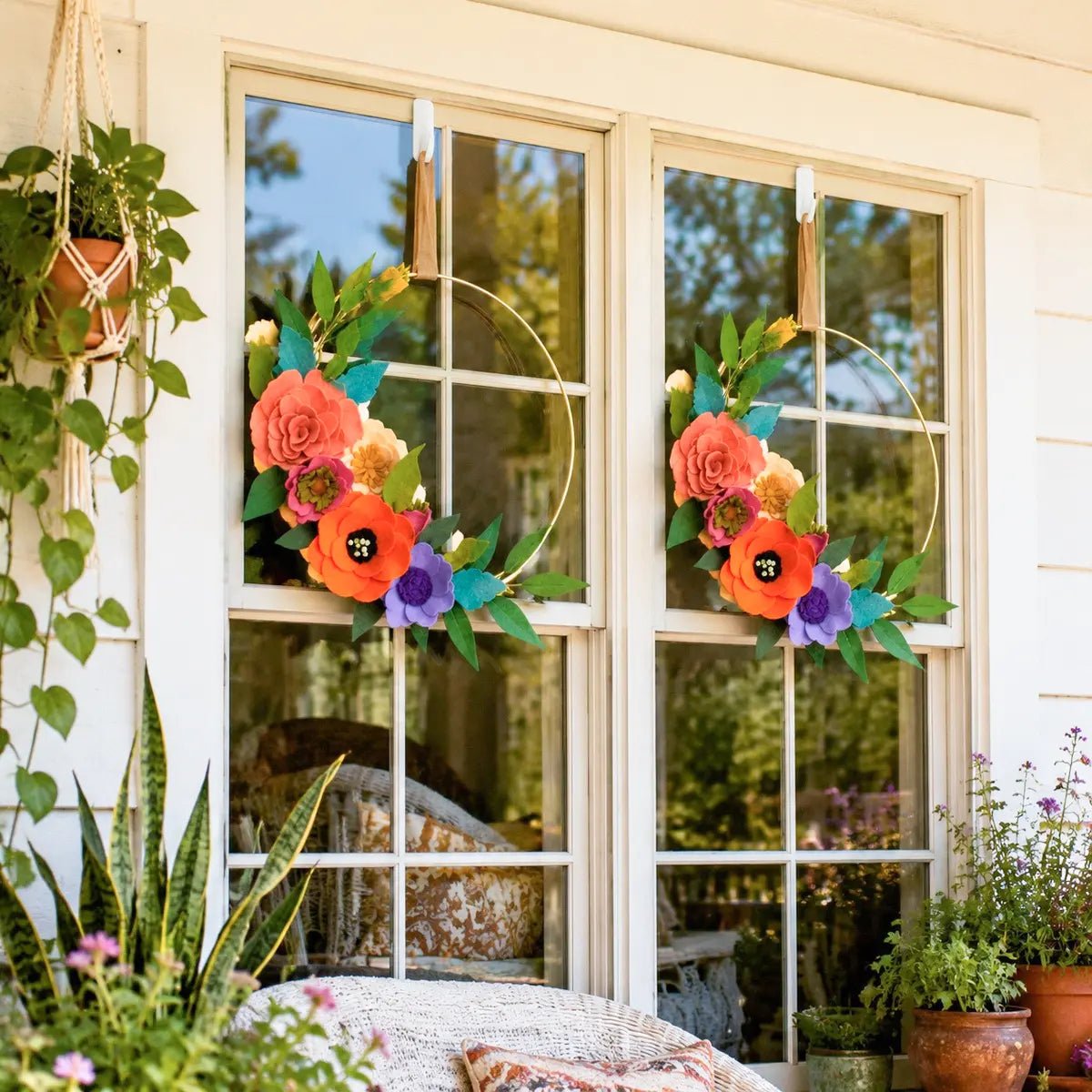 Artificial flower hoop wreath with orange and purple blooms hanging on outdoor window, porch decor
