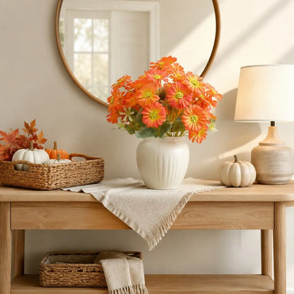 Orange gerbera daisy artificial flowers in a white vase displayed on a console table with mirror in a neutral living room