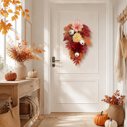 Harvest teardrop swag with white pumpkins, burgundy roses and chrysanthemums hung on a front door in a bright autumn entryway
