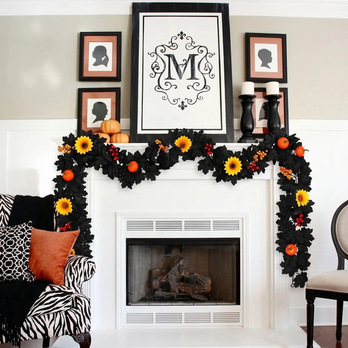 Black fall garland with yellow sunflowers, orange pumpkins, and red and orange berry accents draped across a white fireplace mantel with black candlesticks, stacked pumpkins, and silhouette portrait frames for elegant Halloween home decor