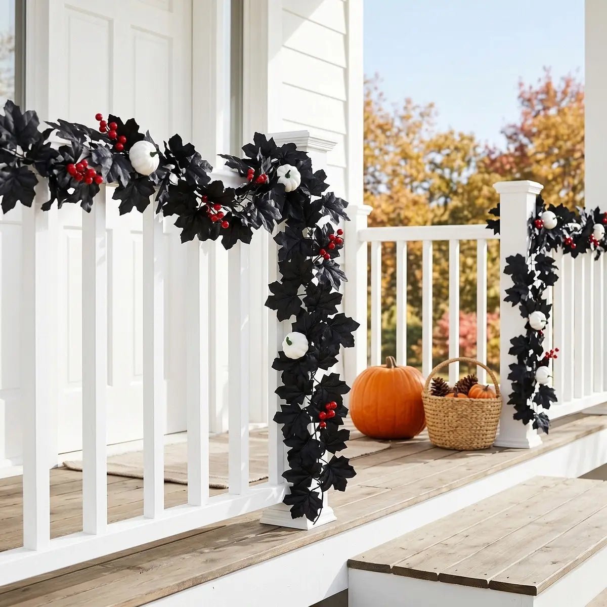 Black maple leaf garland with white pumpkins and red berries wrapped around a white front porch railing with orange pumpkin and wicker basket for Halloween outdoor fall decor