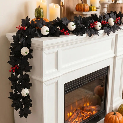 Black maple leaf garland with white pumpkins and red berry clusters draped over a white fireplace mantel with candles, green and orange pumpkins for Halloween fall decor