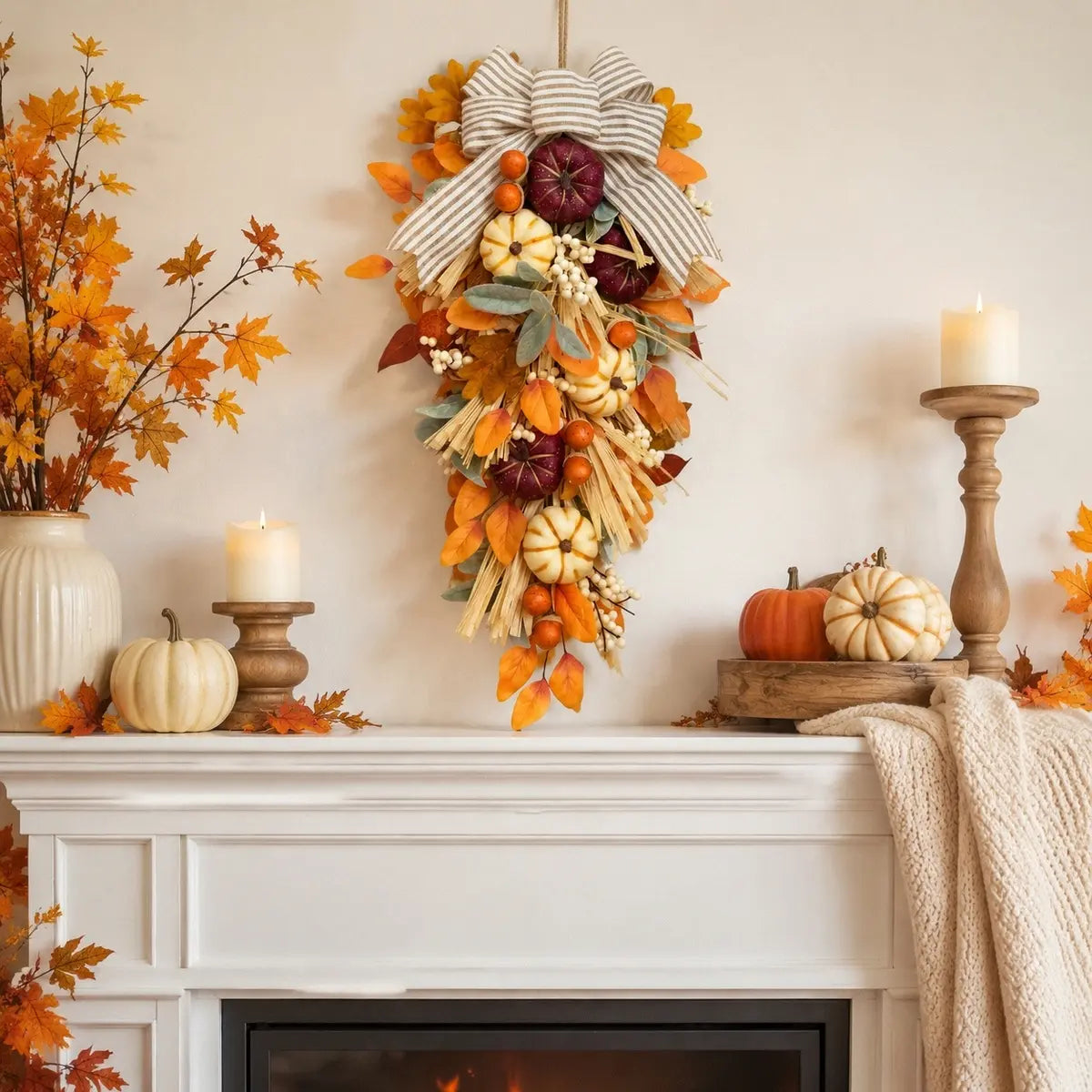 Artificial fall teardrop swag with white pumpkins and striped bow hung on a front door for autumn harvest decor
