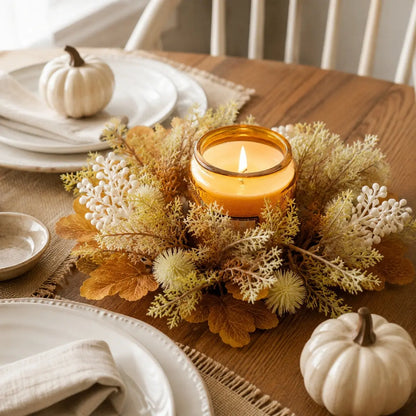 Neutral fall candle ring wreaths with cream berries and thistle displayed around candles on a Thanksgiving harvest dining table setting