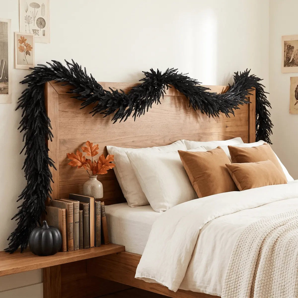 Black faux pine garland draped over a wood headboard with caramel throw pillows, orange faux leaf stems in a vase and a black pumpkin on the nightstand
