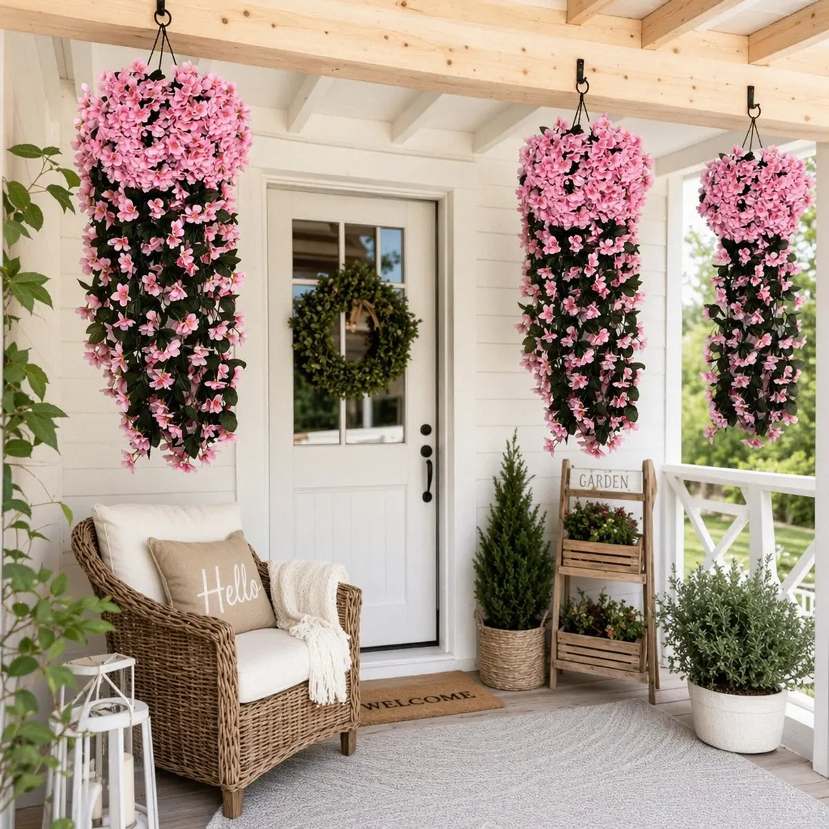 Artificial pink hanging flower vines hung from farmhouse porch ceiling beside front door with wreath, cozy outdoor porch décor
