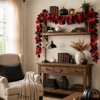 Two red and black maple leaf fall garlands draped in a U-shape around a rustic wooden wall shelf and console table with vintage books, white pumpkins, black pumpkin, brass desk lamp, dried fall branches, and wicker vase for Halloween home styling