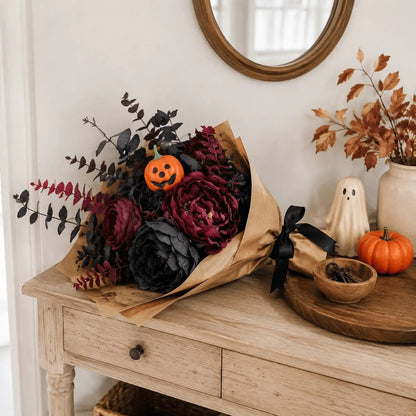 Halloween faux flower bouquet wrapped in kraft paper with black ribbon on rustic wood console table