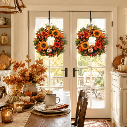 Fall harvest wreaths with pumpkins and berries displayed on a wall with multiple wreath arrangements and autumn styling