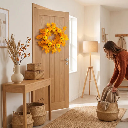 Fall wreath with yellow sunflowers and orange maple leaves hung on a wall next to a floor lamp for autumn home decor
