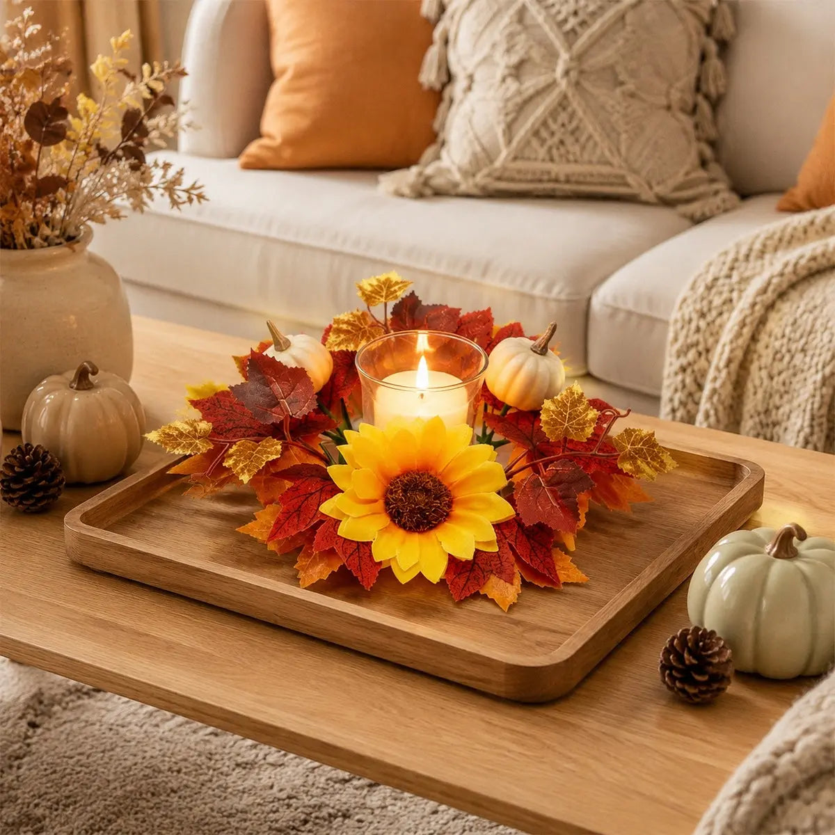 Fall candle ring wreath with sunflower and maple leaves displayed around a candle on a side table in a neutral living room