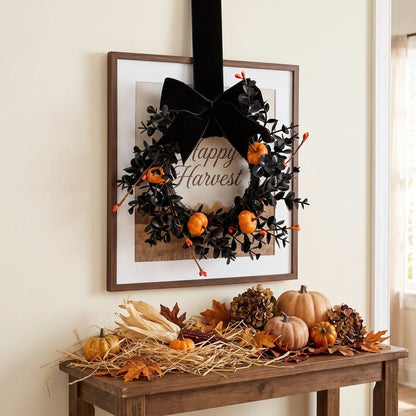 Gothic Halloween mini wreath with black bow and orange pumpkins hanging on a wall frame in a neutral home interior