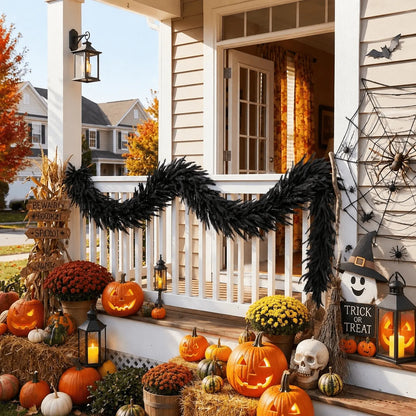 Black Halloween pine garland wrapped along a white porch railing with carved jack-o-lanterns, yellow and red mums, hay bales and a Trick or Treat lantern sign
