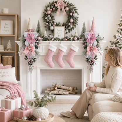 Pair of pink Christmas teardrop swags flanking a white fireplace mantel with pink stockings, pine wreath and frosted garland in a cozy holiday living room
