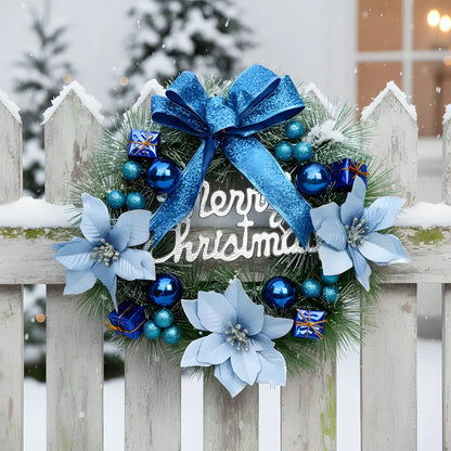 Christmas pine wreath with blue glitter bow, light blue poinsettias, navy ball ornaments and Merry Christmas sign, displayed on a white picket fence in snow
