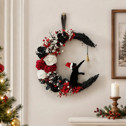 Christmas black cat moon wreath with white and red roses, red berries and gold jingle bell, hung on white wainscoting wall above a dark console table styled with wrapped Christmas gifts, lantern and holiday stockings

