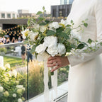 Close-up of white artificial bridal bouquet with faux greenery details