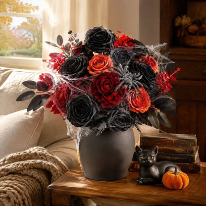 Orange black red artificial roses and peonies combo arranged in a matte black round vase on a wooden side table with a black cat figurine, mini pumpkin, and stacked vintage books for Halloween home styling
