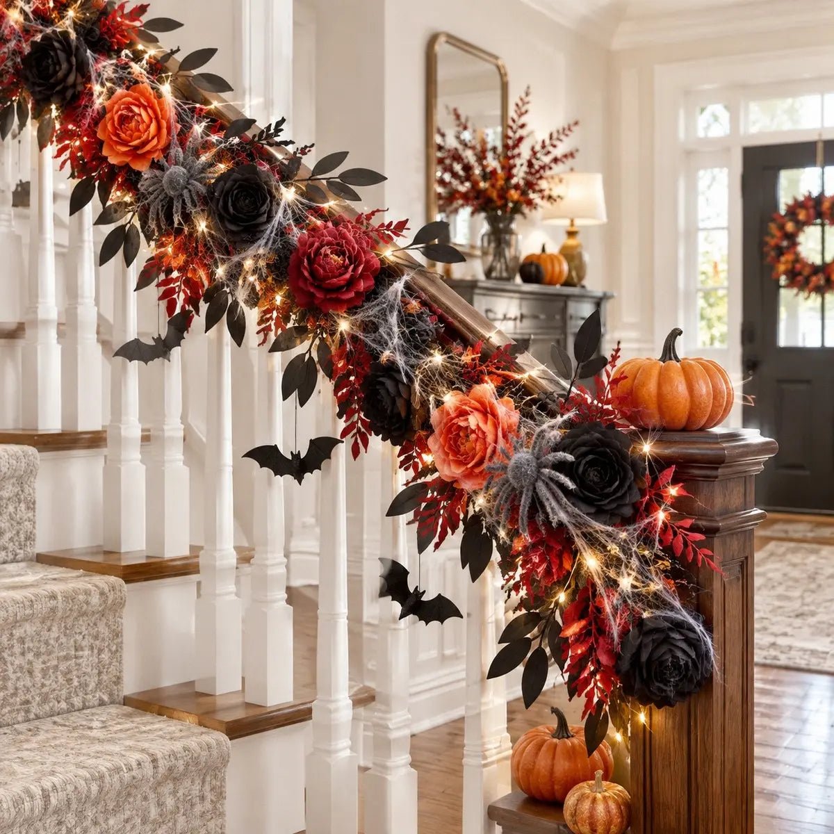 Orange black red artificial peonies and roses combo used as staircase garland decoration with spider webs, bat cutouts, fairy lights, and orange pumpkins for Halloween entryway decor