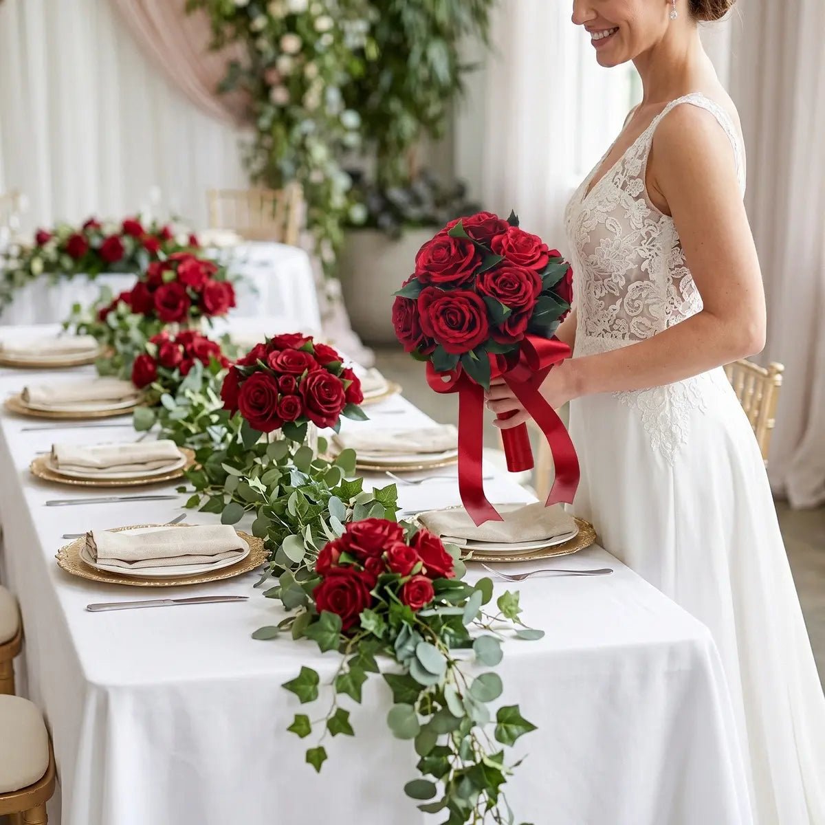 Bride carrying artificial red rose bouquet with long red satin ribbon walking through floral-draped wedding venue corridor
