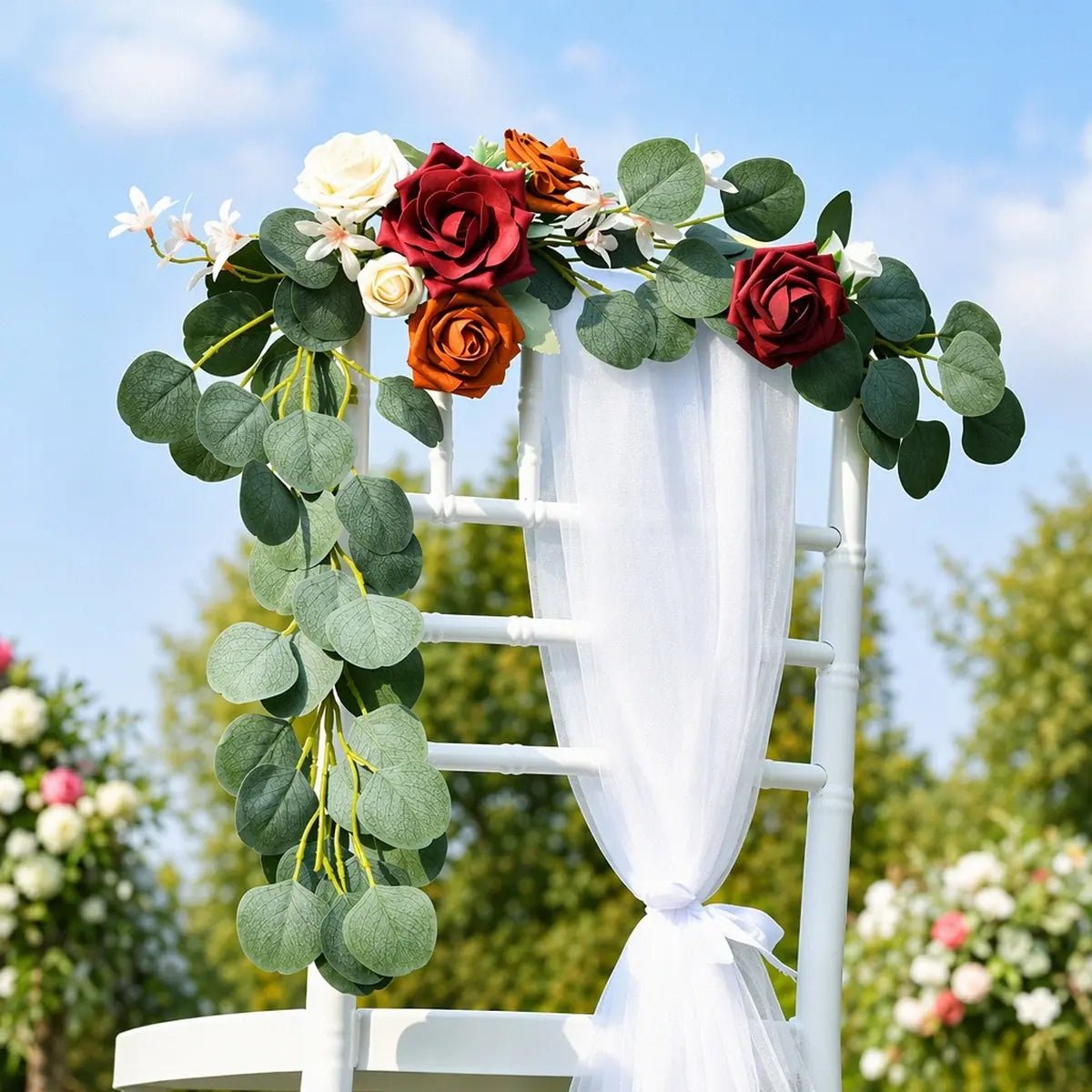 Burgundy terracotta ivory rose silver dollar eucalyptus swag draped over white Chiavari chair back with white chiffon sash tied at base at outdoor garden wedding ceremony – IPOPU