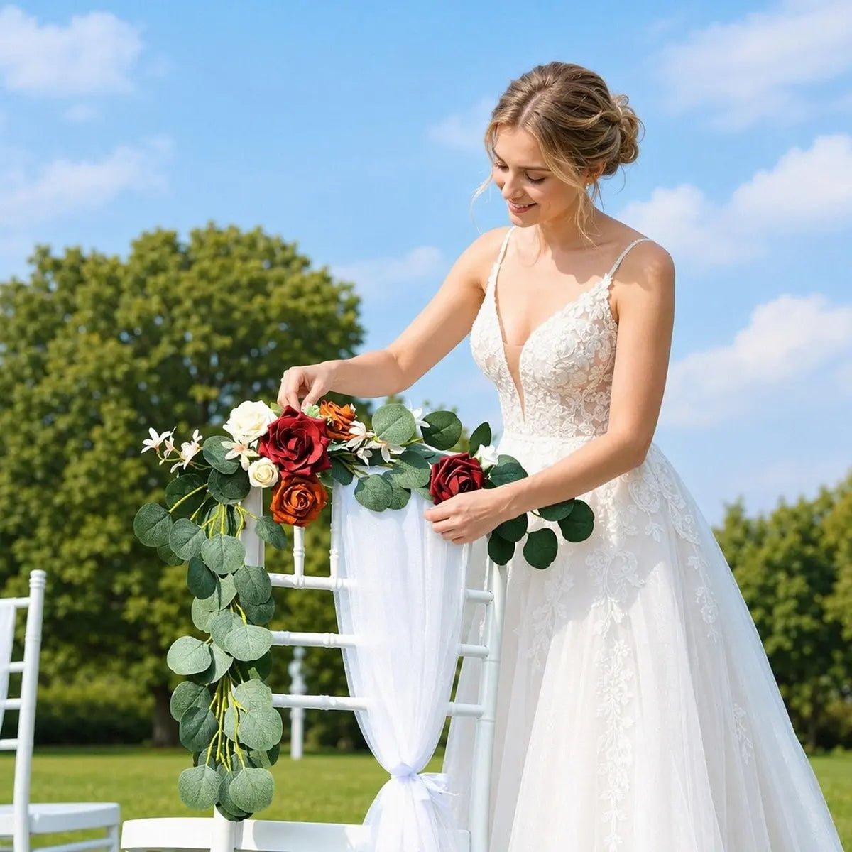 Bride in white lace gown arranging burgundy terracotta rose silver dollar eucalyptus chair swag on white Chiavari aisle chair with white chiffon sash at outdoor garden wedding – IPOPU