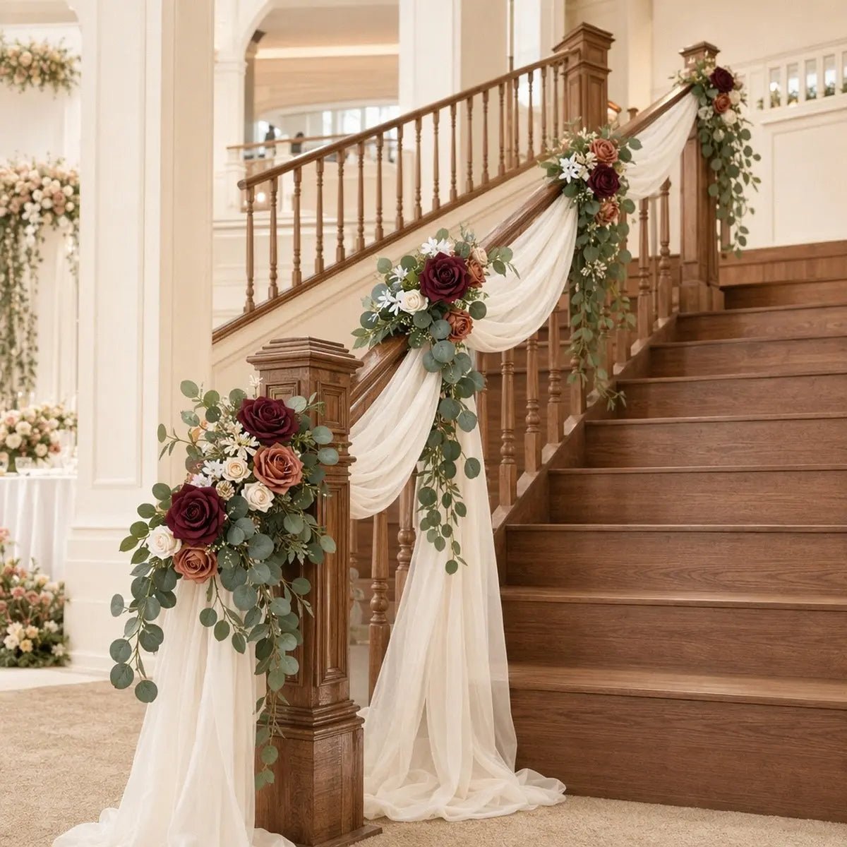Burgundy terracotta rose silver dollar eucalyptus swag set of 2 styled on grand indoor staircase newel post and mid-banister with ivory chiffon drape at wedding venue – IPOPU