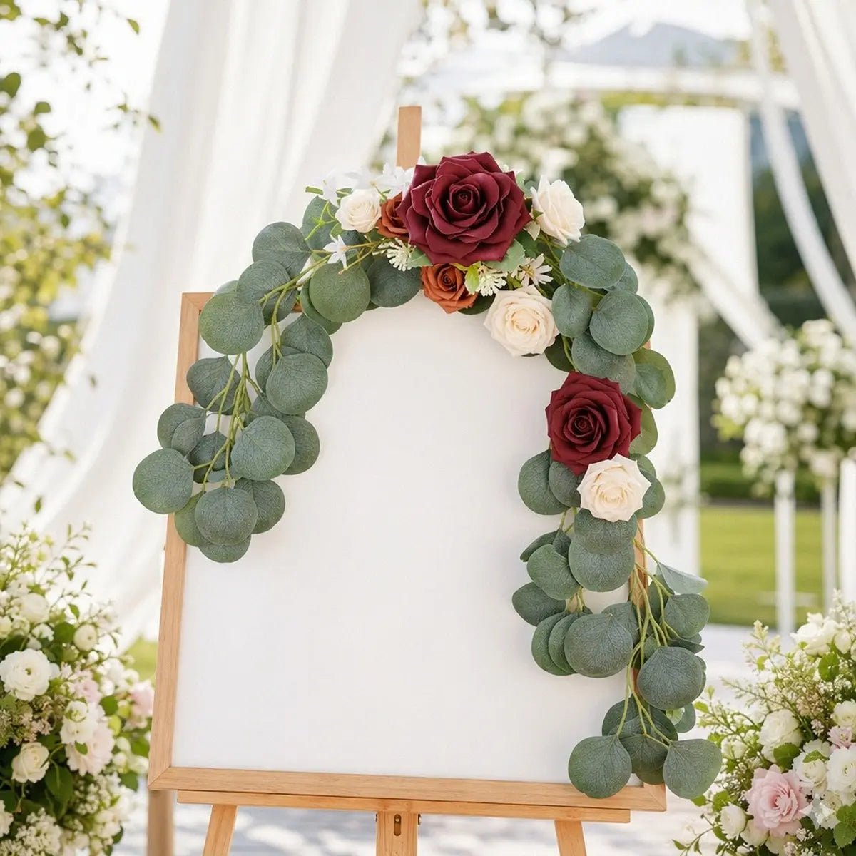 Burgundy terracotta ivory rose silver dollar eucalyptus chair swag set of 2 styled as U-shape frame on white easel welcome sign board at outdoor wedding with white drape backdrop – IPOPU