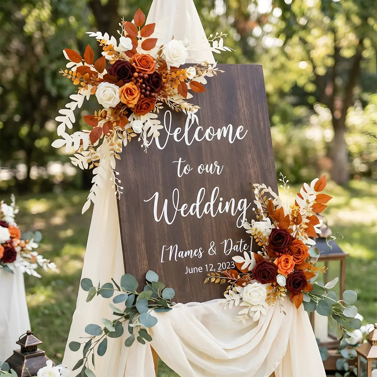 Artificial burnt orange boho flower swag accent on a wooden wedding welcome sign
