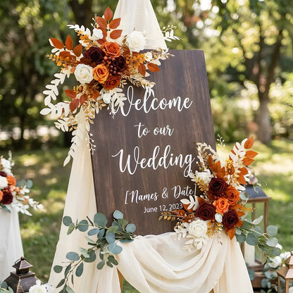 Artificial burnt orange boho flower swag accent on a wooden wedding welcome sign
