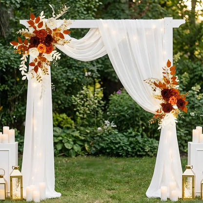 Boho artificial flower swag arrangement on an outdoor wedding arch surrounded by tropical greenery
