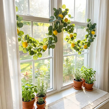Artificial lemon greenery garland with eucalyptus leaves draped across rustic farmhouse dining table as centerpiece, with croissants, lemon bowl and lantern, kitchen home décor