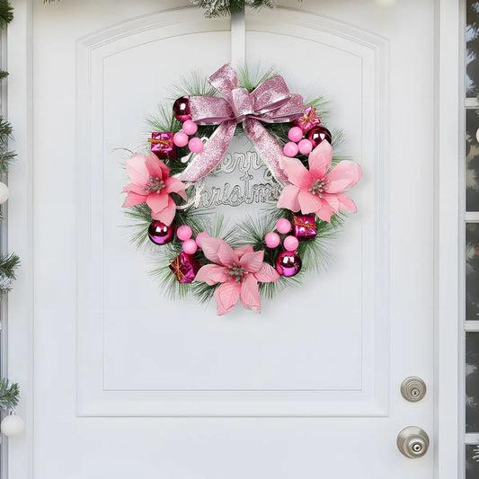 Pink Christmas artificial pine wreath with pink poinsettia flowers, hot pink shiny ball ornaments, pink berry clusters, mini gift boxes and glitter pink bow knot with silver Merry Christmas lettering, hung on a white arched front door with frosted pine garland on the sides