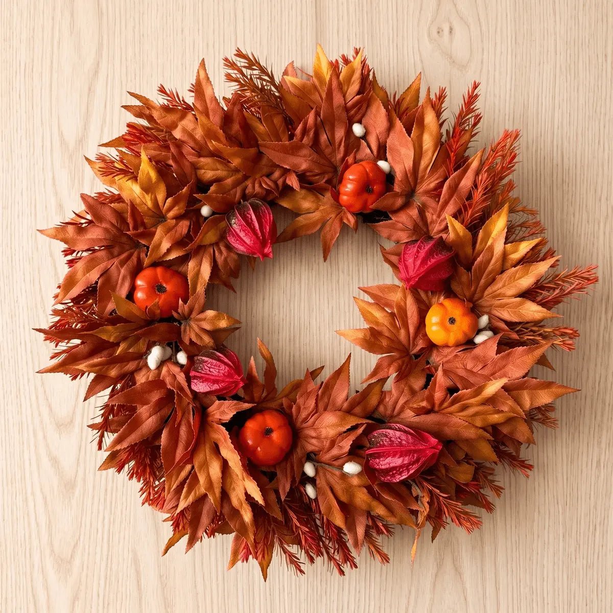 Large fall wreath for front door with artificial maple leaves, fake pumpkins, faux acorns and sunflower on a twig base, product flat lay showing full wreath detail