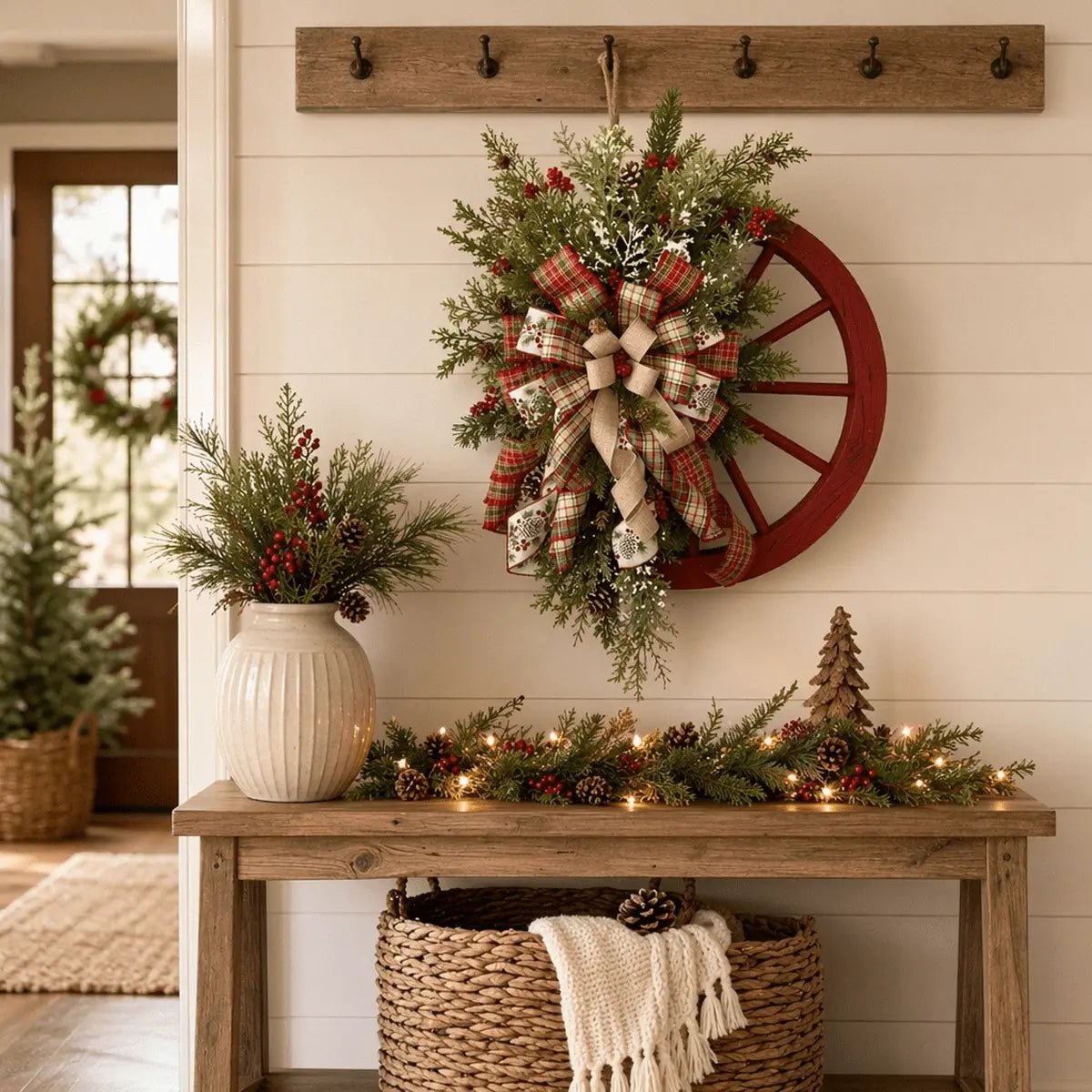 Farmhouse wooden wagon wheel Christmas wreath with snowflake, berries and buffalo plaid bow hung on a white front door for holiday decor