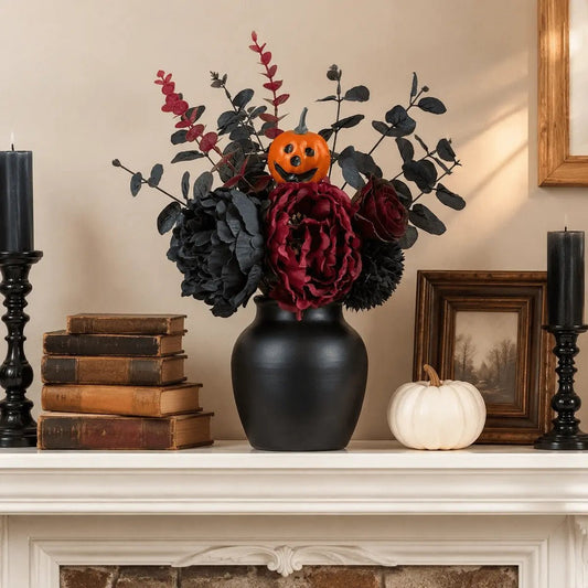 Gothic faux flower bouquet in black vase on fireplace mantel with dark candles and white pumpkin