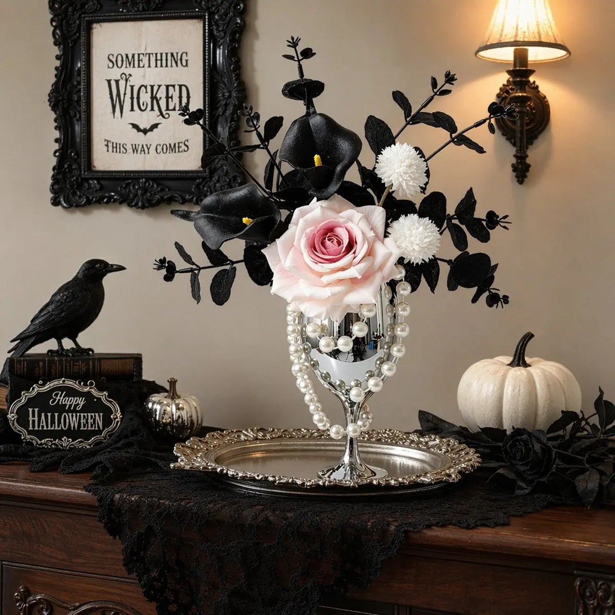 Pink rose gothic artificial flower arrangement with black calla lilies in silver goblet vase displayed in a dark academic styled room