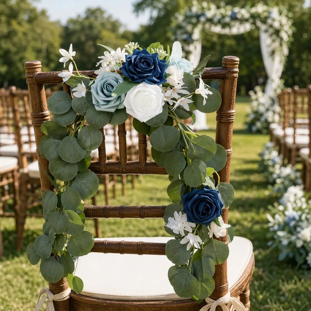 Navy blue dusty blue white rose silver dollar eucalyptus chair swag draped in U-shape over Chiavari bamboo chair back at outdoor garden wedding ceremony aisle – IPOPU