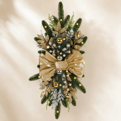 Gold bow Christmas teardrop swag displayed on a holiday door